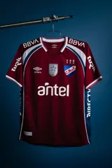 Camiseta de fútbol Umbro de golero del Club Nacional de Football, modelo oficial 2026. Diseño en color bordó con detalles blancos y azules en los hombros, cuello en V y patrocinadores impresos.
