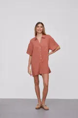 Mono corto color naranja, con cuello camisero, mangas cortas y cierre frontal con botones.