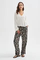 Blusa blanca de viscosa, con cuello en V, detalles de frunces en el frente, botones decorativos y mangas largas holgadas.