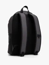 Mochila Tommy Hilfiger de diseño minimalista y silueta tipo domo en color gris oscuro. Cuenta con compartimento principal con cierre de cremallera, un bolsillo exterior frontal con solapa y cierre magnético, correas de hombro acolchadas y ajustables, y un asa superior. Presenta el logo de la marca en relieve en el frente y detalles distintivos.