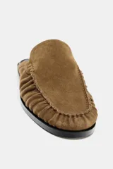 Mocasín destalonado de serraje color marrón, con diseño de copete subido, detalle de antifaz con pespunte y punta redonda.