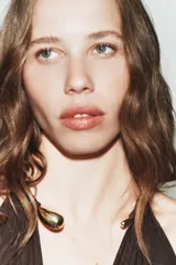 Body entallado de poliamida color marrón, con escote profundo y detalle de cuello metálico tipo choker integrado.