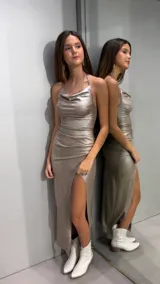 Vestido largo de lurex color dorado, con escote drapeado, tiritas finas para atar al cuello y tajo lateral en la pierna.