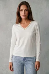 Remera de manga larga con escote en V, confeccionada en tejido suave y fluido con detalle de ribete brillante en el cuello.