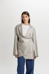 Blazer de corte oversize y estilo masculino, confeccionado en tejido con brillo metalizado y sutil patrón de rayas. Presenta solapas de muesca, cierre frontal de dos botones y bolsillos con solapa en los laterales.