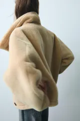 Cazadora reversible de cuello subido y manga larga, con bolsillos de vivo en el delantero y cierre frontal con botones. Confeccionada en tejido combinado con efecto pelo y efecto ante.