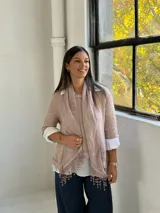 Sweater de punto rosa claro con diseño de capas, que incluye una camisa blanca debajo y un pañuelo a juego con detalles de encaje y flecos en el ruedo.