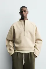 Sudadera de corte cropped confeccionada en tejido técnico compacto de algodón con elasticidad. Presenta cuello subido con cierre frontal de cremallera, manga larga y acabados en rib del mismo tejido.