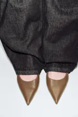 Zapato destalonado de piel en color marrón, con diseño de punta fina y tacón kitten. Incluye una tira trasera ajustable con hebilla metálica dorada.