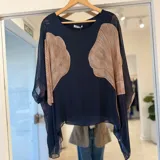 Blusa azul marino de mangas murciélago transparentes y corte holgado, con inserciones en tono tostado de diseño curvo en el frente.