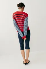 Chaqueta de punto con cuello redondo y mangas largas, con diseño de rayas horizontales en colores rojo, celeste y azul marino, y cierre frontal con botones.
