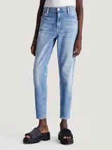 Jeans vintage de talle alto con pierna estrecha en el tobillo, confeccionados con denim de algodón elástico y fibras recicladas. Diseño de cinco bolsillos, bragueta con cremallera, lavado azul claro y bordado de Calvin Klein en la parte trasera de la cintura.