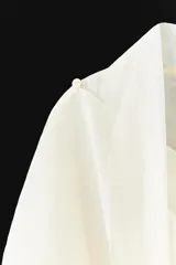 Camisa de mujer confeccionada en mezcla de lyocell, con diseño fluido y cuello tipo pañuelo integrado. Presenta manga larga con puños, bajo redondeado asimétrico y cierre frontal con botones ocultos bajo solapa.