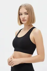 Top deportivo negro de tejido acanalado, con escote redondo y diseño ajustado al cuerpo.