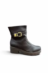 Bota corta de cuero color marrón con suela track y taco bloque. Incluye una tira decorativa en el tobillo con hebilla metálica dorada.