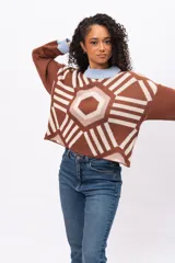 Buzo tejido de punto con diseño geométrico tipo mandala en tonos marrón, beige y blanco. Presenta cuello redondo y puños en color celeste pastel, con corte holgado y mangas largas.