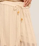 Pantalón recto color beige con textura, confeccionado en algodón BCI más sostenible, con cintura alta elástica y lazo de ajuste.
