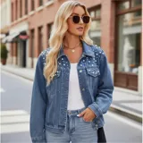 Campera de jean color negro con apliques de perlas en la parte superior frontal. Presenta cuello clásico, cierre frontal con botones metálicos y dos bolsillos en el pecho.