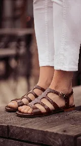 Sandalia plana tipo romana confeccionada 100% en cuero color negro, con múltiples tiras entrelazadas y cierre de hebilla lateral.