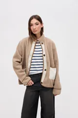 Campera de sherpa doble faz en color beige, con cierre frontal de botones y detalles en nylon color crema. Presenta bolsillos laterales de nylon, cuello alto y diseño relaxed.