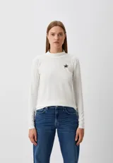 Polera blanca de tejido de punto fino, con cuello alto y manga larga. Tiene un pequeño logo de estrella bordado en el pecho.