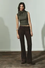 Top de punto sin mangas color verde oliva, con cuello solapa que se ajusta con un botón y terminaciones acanaladas en el cuello y el bajo.