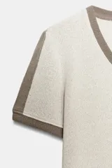 Camiseta slim fit de color blanco crudo con escote en pico y ribetes marrones en el cuello y las mangas.