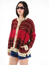 Cardigan tejido de punto jacquard en tonos bordó y rojo con rayas, de corte oversize, cuello redondo y cierre frontal con botones carey. Presenta detalles bordados en contraste y monograma en la espalda.