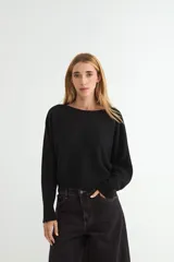 Sweater de punto negro, de corte holgado y diseño cropped, con cuello redondo y mangas largas.