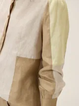 Camisa de lino con diseño color block en tonos beige, arena y amarillo claro. Presenta mangas largas con puños abotonados, corte recto y dobladillo redondeado.