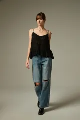Musculosa negra de breteles finos, confeccionada en algodón con diseño plisado y detalles de encaje. Presenta un corte holgado con volados en el ruedo y escote profundo.