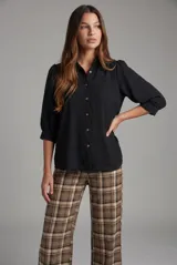 Blusa negra de corte oversize, con mangas tres cuartos abullonadas y cierre frontal de botones.
