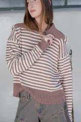 Sweater de tejido de punto con diseño a rayas horizontales en color marrón y blanco, cuello con solapa y mangas largas.