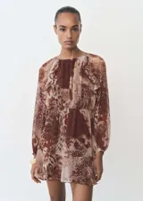 Vestido corto de gasa con estampado animal print en tonos marrones. Presenta cuello redondo con detalle fruncido, mangas largas con puños elásticos, volantes decorativos en el pecho y falda con volado en el ruedo. Incluye forro interior.
