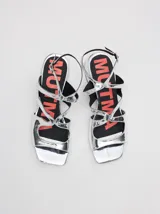 Sandalias de cuero con acabado charol color bordó, con punta cuadrada, tiras onduladas en el empeine y correa ajustable con hebilla en el tobillo. Cuentan con un taco bajo forrado.