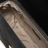 Bandolera de símil gamuza color negro, con solapa frontal y cierre magnético. Presenta un detalle frontal con el logo "XL" en dorado. Incluye un asa corta desmontable y una correa larga regulable y desmontable. Cuenta con herrajes metálicos dorados y un bolsillo interno con cierre.