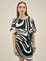 Top de escote redondo y manga corta, con estampado abstracto en blanco y negro. Presenta un corte asimétrico en la espalda y está confeccionado en lino viscosa.