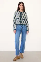 Saco de punto con diseño de rombos en tonos verde, amarillo y gris. Presenta cuello redondo, cierre frontal con botones y dos bolsillos delanteros con terminaciones en contraste.