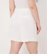 Bermuda de tiro alto confeccionada en crepé color blanco, con cierre frontal, bolsillos laterales y detalle de botones decorativos.
