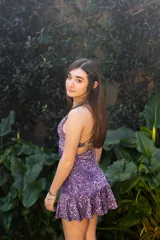 Vestido corto negro con estampado de plumas doradas, escote en V, breteles finos cruzados en la espalda, cut-outs laterales y volado en el ruedo.