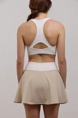Top deportivo corto de sujeción media, con escote redondo y espalda abierta. Confeccionado en tejido elastizado de poliamida y spandex, con elástico interno en la cintura para mayor ajuste.