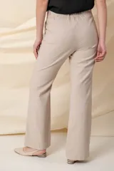 Pantalón de vestir color beige, de corte palazzo y cintura elastizada.