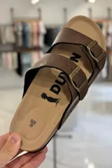 Sandalia marrón con diseño de dos tiras ajustables con hebillas metálicas y plantilla anatómica.