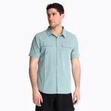 Camisa de manga corta Merrell color verde claro, con cuello clásico, cierre frontal con botones y dos bolsillos en el pecho con solapa. Confeccionada en mezcla de poliéster reciclado y spandex.