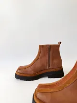 Botas cortas de cuero color marrón con elástico en los laterales y detalle de cuero texturizado en la parte delantera.