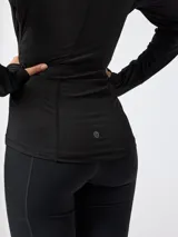 Campera deportiva negra de manga larga con cuello alto, cierre frontal completo y bolsillos laterales con cierre. Presenta detalles de costuras anatómicas y puños con abertura para el pulgar.