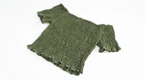 Top de color azul con diseño fruncido en toda la prenda, escote estilo hombros caídos y mangas cortas con terminación de volados.