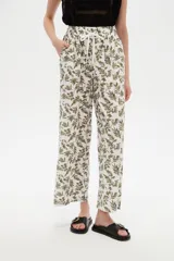 Pantalón de algodón estampado con diseño botánico de hojas en tonos verdes sobre base blanca, de corte holgado, tiro medio y cintura elástica con cordón de ajuste ajustable.