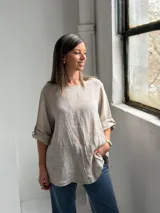 Blusa de lino color beige, de corte holgado, cuello redondo y mangas 3/4 con presillas y botones para sujetar el largo.