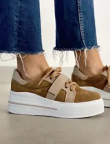 Sneakers de mujer estilo deportivo y urbano, color negro con detalles en beige claro. Presentan puntera y talón en negro, cuerpo principal en negro, y estrella lateral, cordones y tira de velcro en beige claro. La suela es blanca y el interior negro con la inscripción "LUCY IN THE SKY".